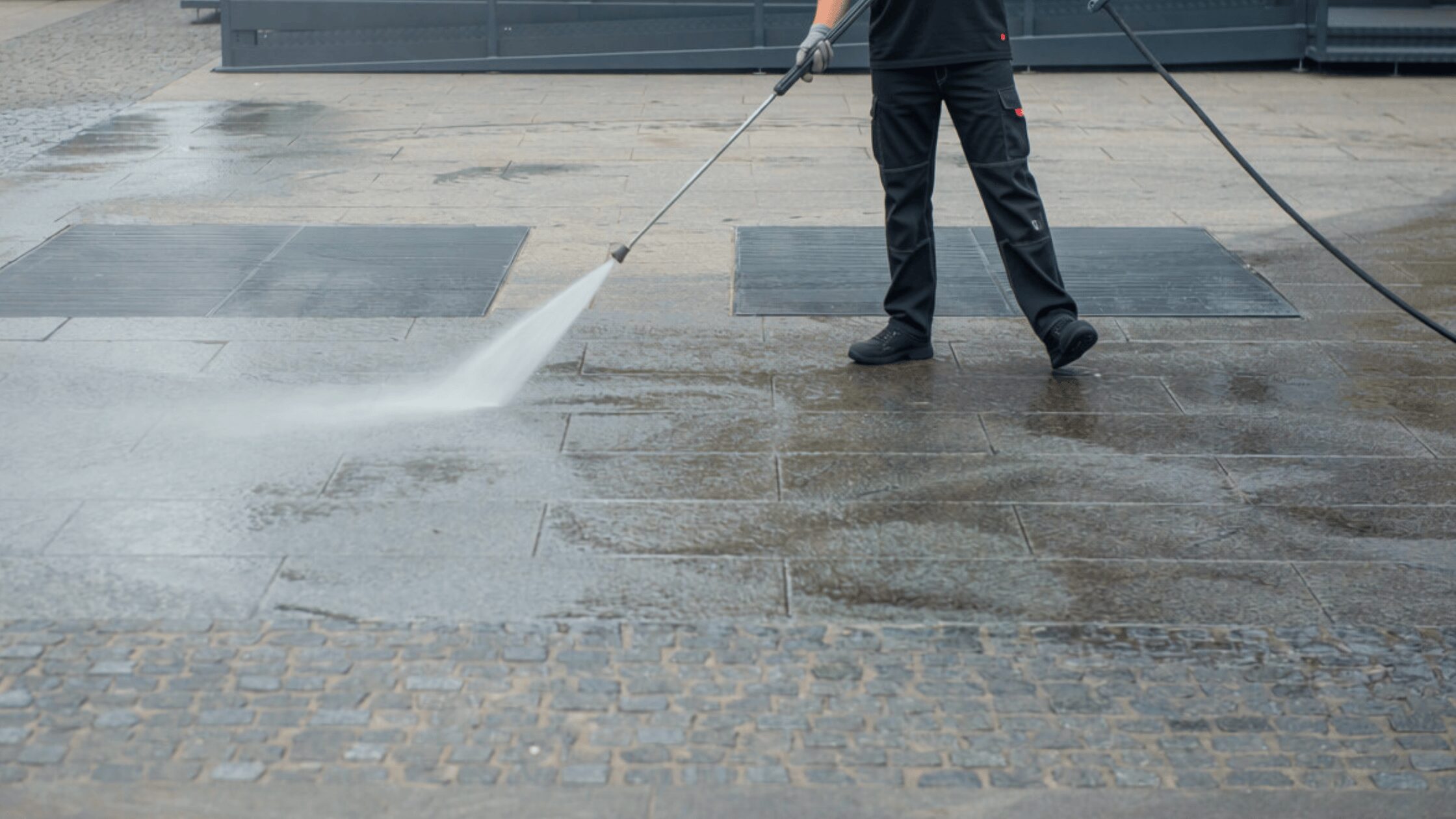 Worker pressure washing stamped concrete patio in Fond du Lac, Wisconsin, cleaning and restoring decorative paver surface